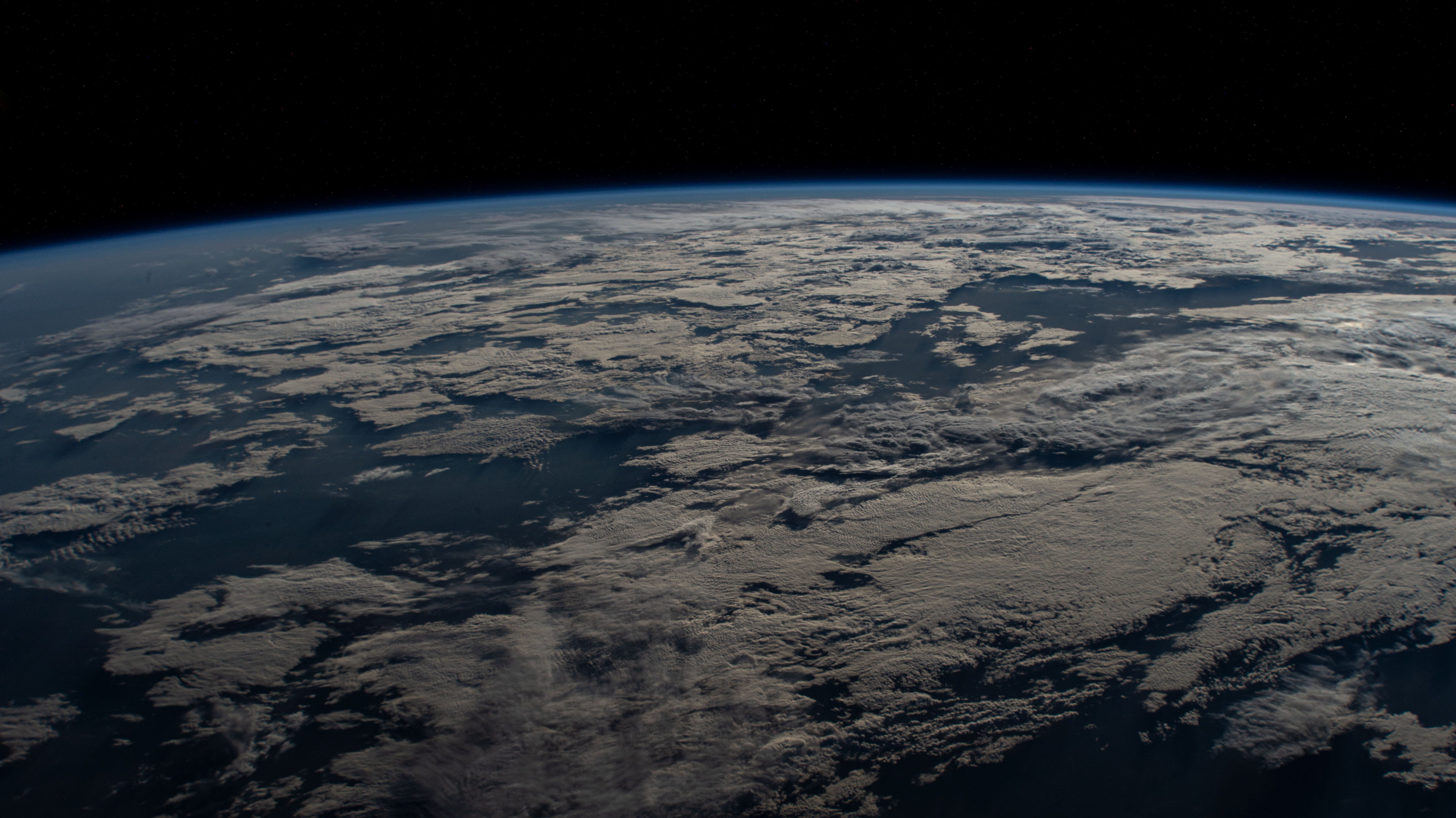 Earth’s curved horizon, blue atmosphere, and cloud layers photographed from the International Space Station